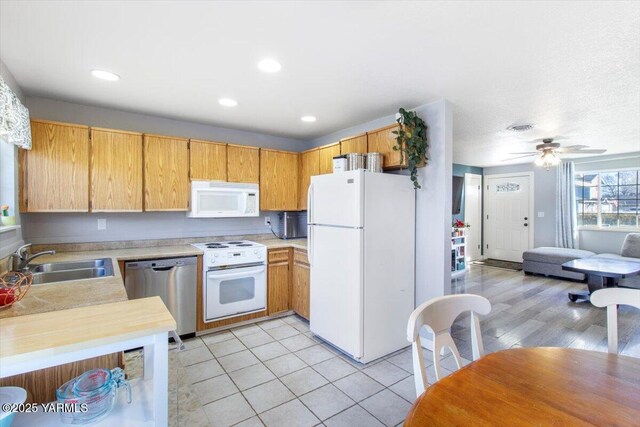 kitchen featuring light tile patterned floors, recessed lighting, white appliances, a sink, and light countertops