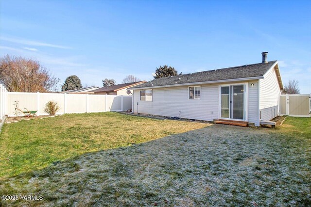 back of house with a fenced backyard and a lawn