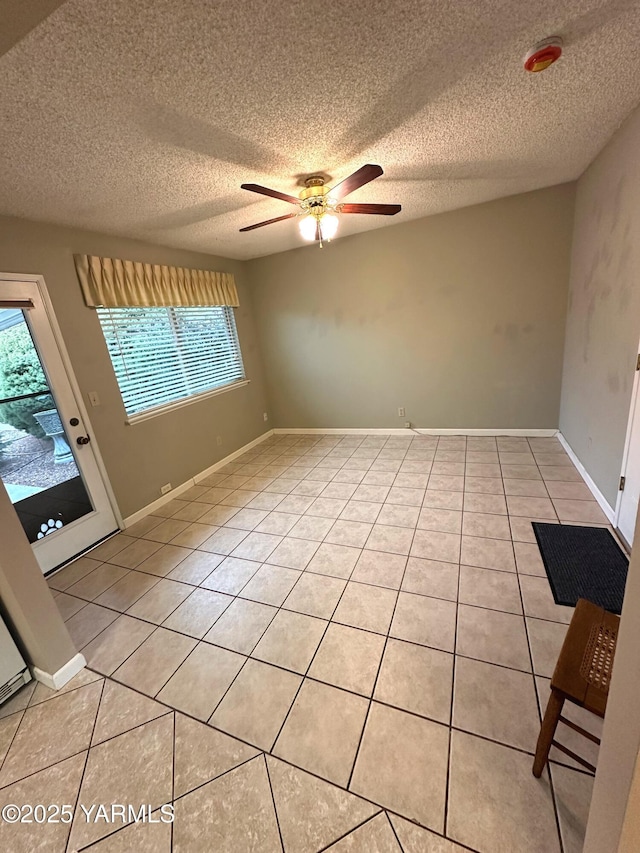 empty room featuring light tile patterned floors, ceiling fan, and baseboards