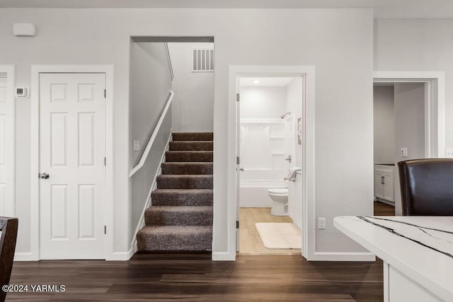 staircase with baseboards, visible vents, and wood finished floors