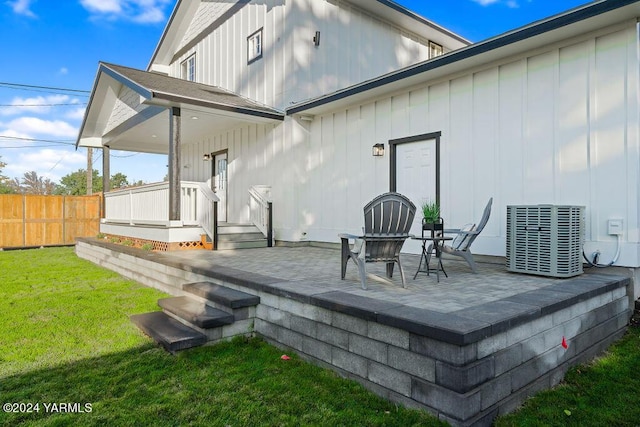 rear view of property with board and batten siding, cooling unit, a yard, and fence