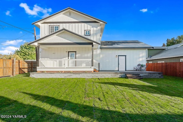 back of house with covered porch, a yard, board and batten siding, and a fenced backyard