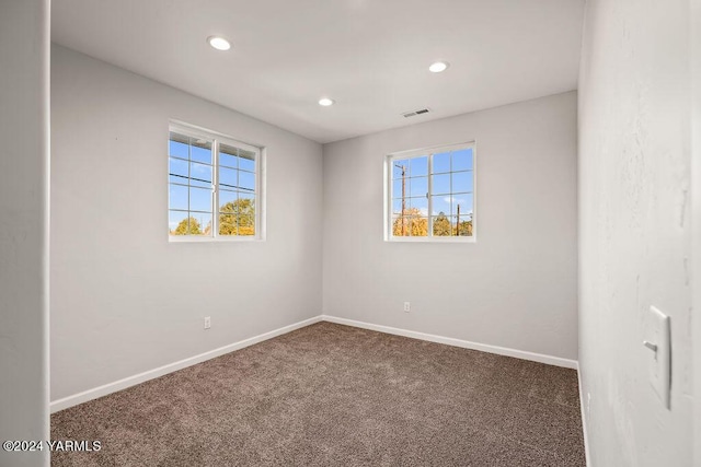 spare room featuring plenty of natural light, carpet flooring, and visible vents