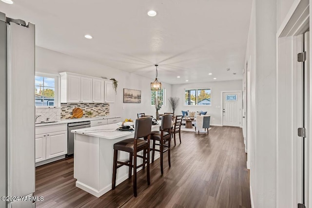 kitchen with tasteful backsplash, white cabinets, a kitchen island, decorative light fixtures, and stainless steel appliances