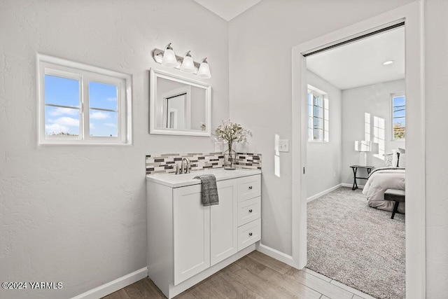 bathroom with baseboards, a sink, wood finished floors, and decorative backsplash