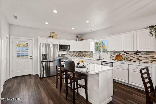 kitchen with white cabinets, stainless steel appliances, a sink, and a center island