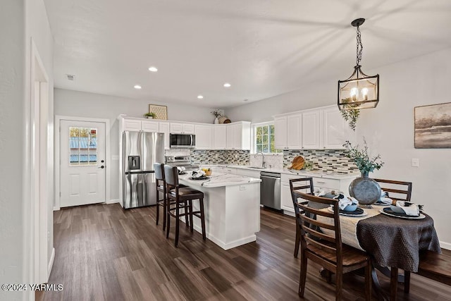 kitchen featuring stainless steel appliances, a kitchen island, white cabinets, and pendant lighting