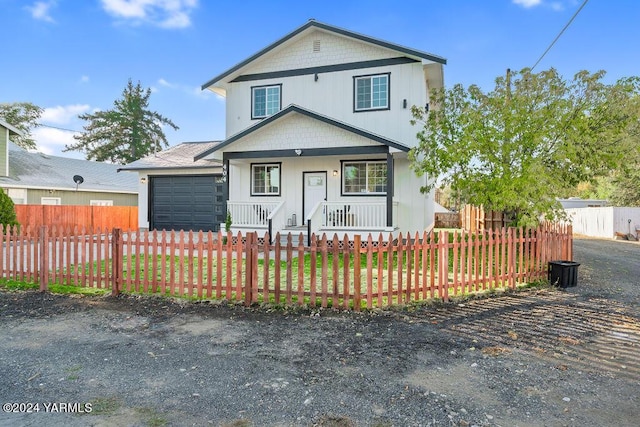 view of front facade with a porch, a fenced front yard, and an attached garage