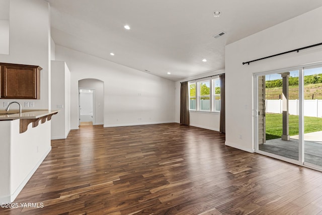 unfurnished living room with vaulted ceiling, dark wood-style floors, arched walkways, recessed lighting, and baseboards