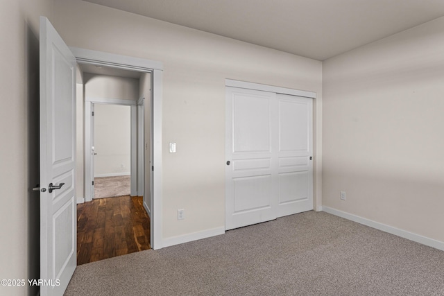 unfurnished bedroom with dark colored carpet, baseboards, and a closet