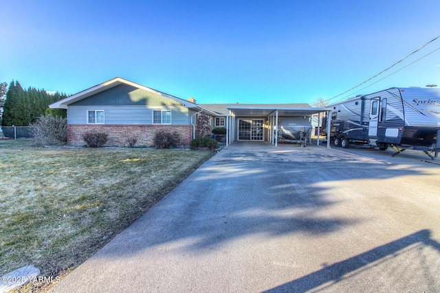 ranch-style house featuring a carport, a front yard, brick siding, and driveway