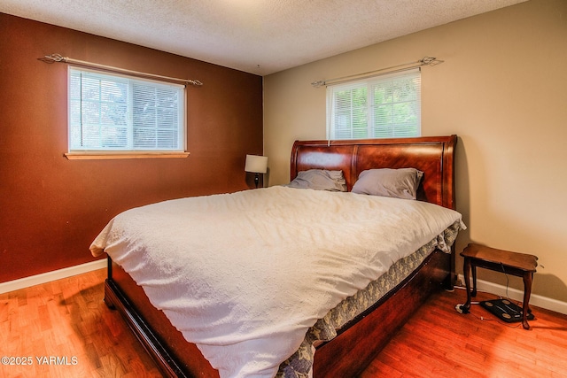 bedroom featuring a textured ceiling, baseboards, and wood finished floors