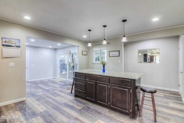 kitchen with light wood-style floors, baseboards, and a kitchen breakfast bar