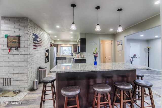 kitchen with light wood-type flooring, brick wall, and light stone counters