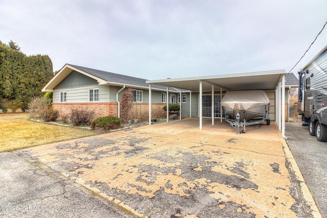 view of front of home featuring driveway, a front yard, a carport, and brick siding