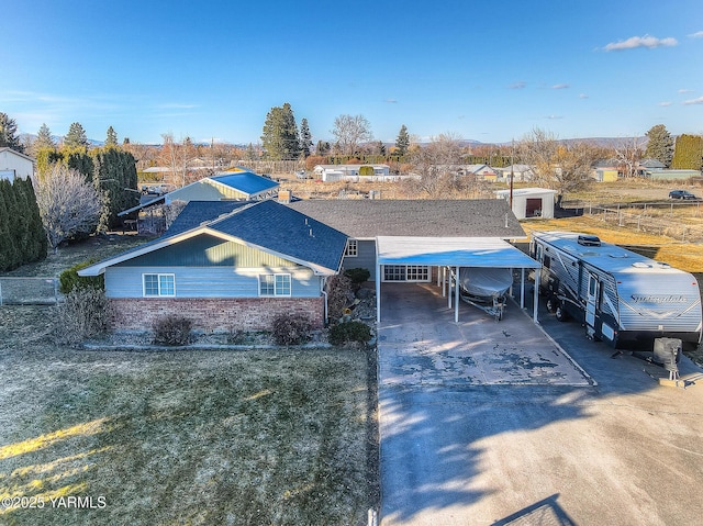 view of front of house with driveway, brick siding, and a detached carport