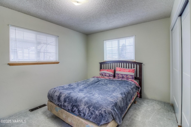 bedroom with carpet, a closet, visible vents, and a textured ceiling