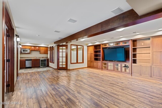 unfurnished living room with light wood-style floors, wine cooler, beam ceiling, and baseboards