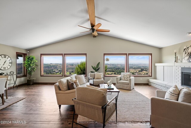 living room with vaulted ceiling with beams, a brick fireplace, a healthy amount of sunlight, and dark wood-style flooring