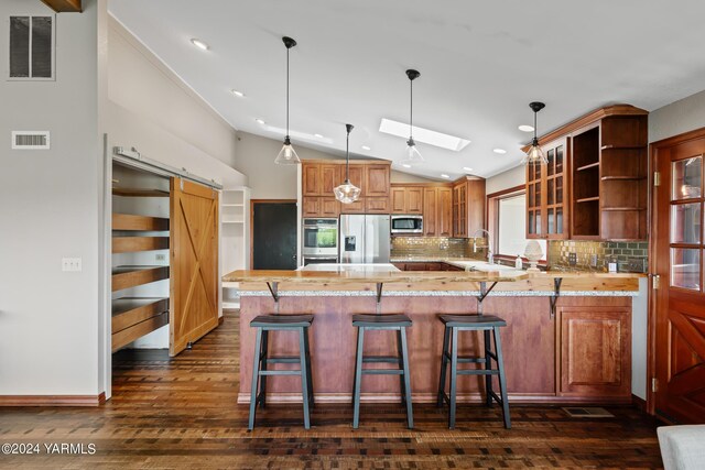 kitchen featuring open shelves, visible vents, a barn door, appliances with stainless steel finishes, and a peninsula