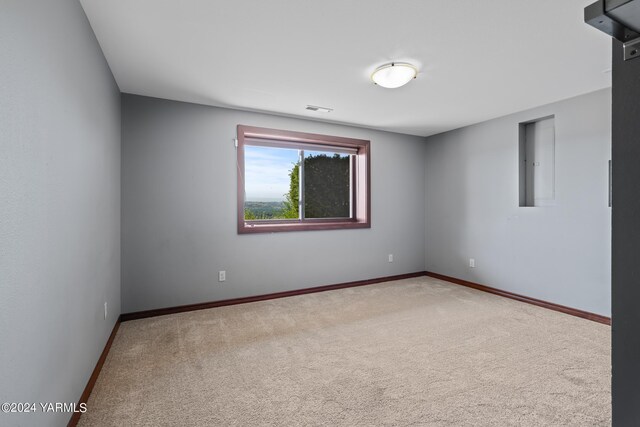 carpeted empty room featuring visible vents, electric panel, and baseboards