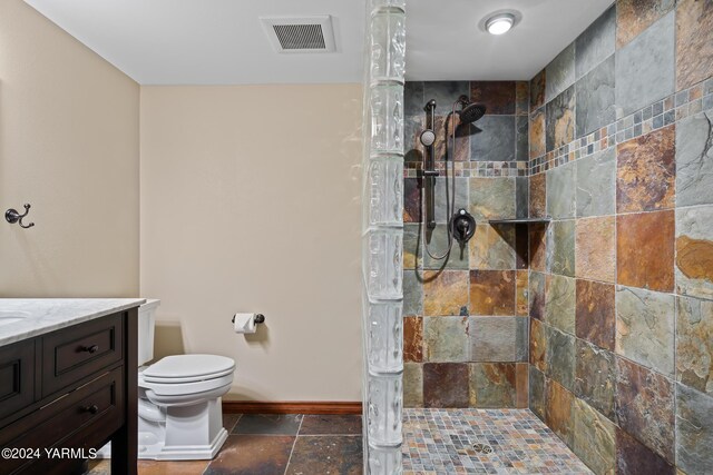 bathroom featuring stone tile flooring, visible vents, toilet, a walk in shower, and baseboards