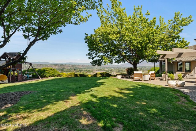 view of yard featuring a playground, a mountain view, exterior kitchen, and a patio