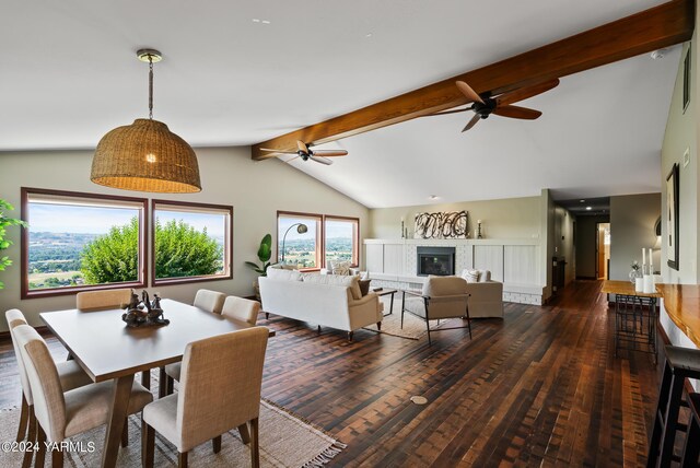 dining room with a ceiling fan, a glass covered fireplace, dark wood-style flooring, and lofted ceiling with beams