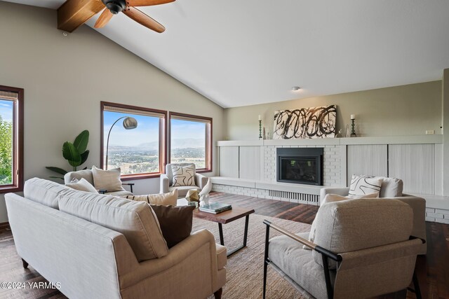 living area with a ceiling fan, wood finished floors, a fireplace, high vaulted ceiling, and beam ceiling