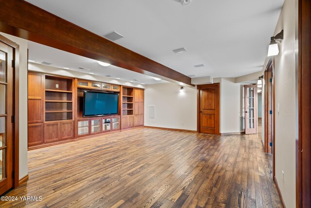 unfurnished living room featuring visible vents, beam ceiling, baseboards, and wood finished floors