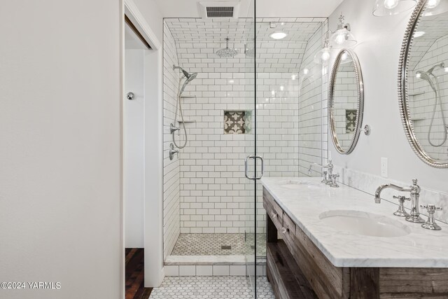 bathroom with double vanity, a stall shower, a sink, and visible vents