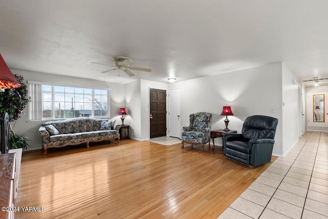 living room with light wood-type flooring, ceiling fan, and baseboards