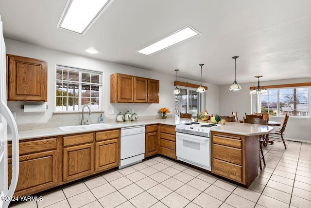 kitchen featuring white appliances, decorative light fixtures, a peninsula, light countertops, and a sink