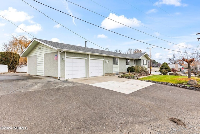 ranch-style home featuring a front yard, driveway, an attached garage, and stucco siding