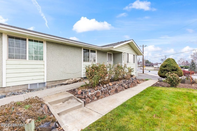 view of property exterior with stucco siding and a yard