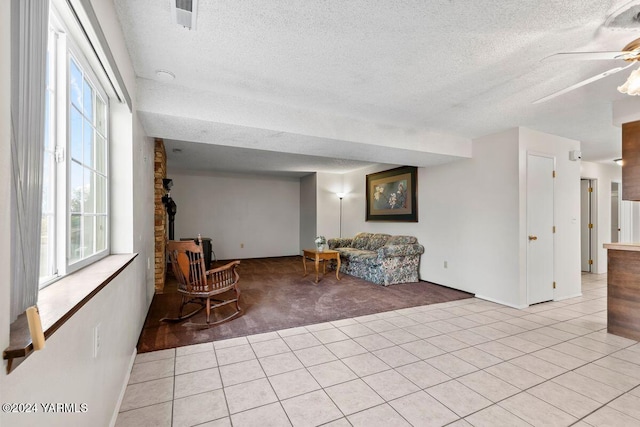 sitting room with light carpet, light tile patterned floors, ceiling fan, and a textured ceiling