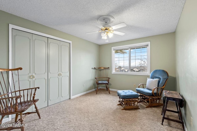 sitting room featuring carpet floors, a textured ceiling, baseboards, and a ceiling fan