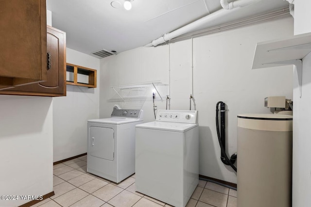 laundry room featuring light tile patterned floors, visible vents, baseboards, cabinet space, and washing machine and clothes dryer