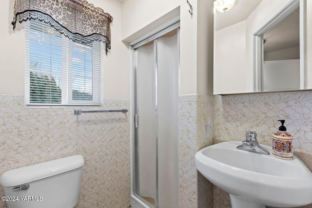 full bathroom with tile walls, toilet, wainscoting, a sink, and a shower stall