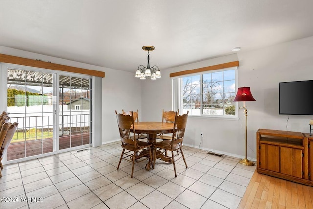 dining area with light tile patterned floors, baseboards, and an inviting chandelier