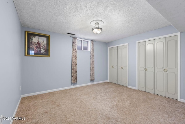 unfurnished bedroom with visible vents, light carpet, baseboards, and two closets