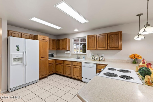 kitchen with white appliances, a sink, light countertops, hanging light fixtures, and brown cabinetry