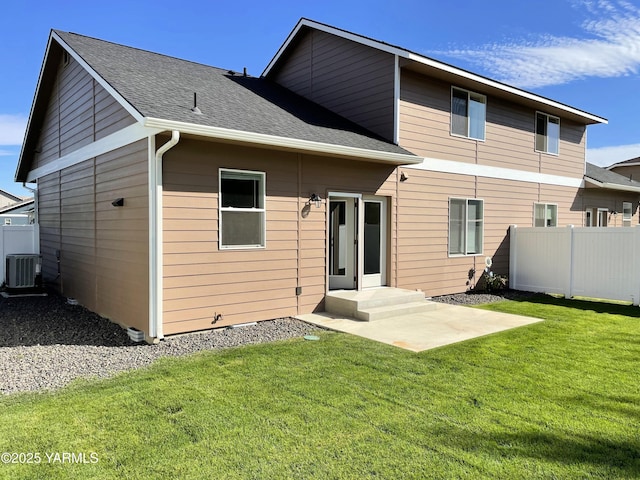 rear view of house with a lawn, fence, a shingled roof, and cooling unit