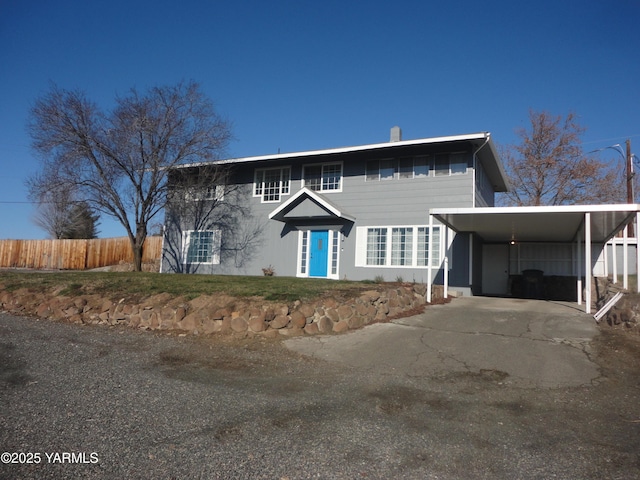 view of front facade with driveway, an attached carport, and fence