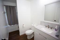 full bath featuring shower / bath combination with curtain, vanity, toilet, and wood finished floors