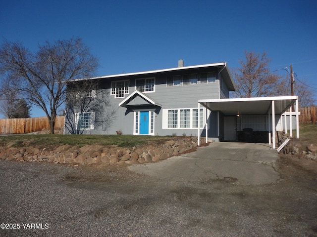 view of front facade with an attached carport, fence, and driveway