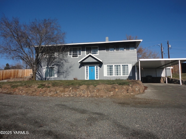 view of front facade featuring driveway, fence, and an attached carport