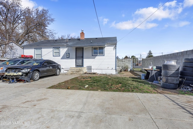 rear view of house featuring a chimney and fence