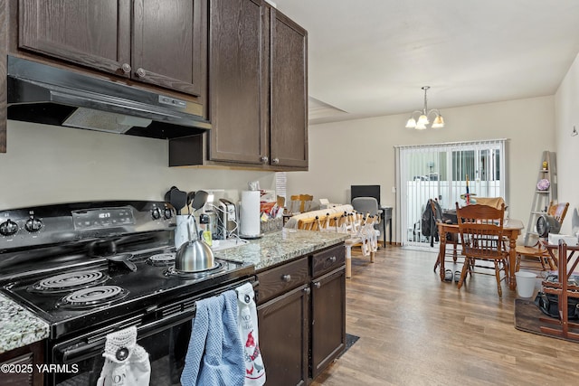 3103 Swan Ave, Yakima, WA 98902 - kitchen with black range with electric cooktop, under cabinet range hood, dark brown cabinets, and light wood-type flooring