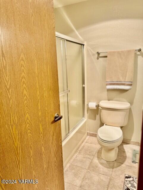 full bathroom featuring baseboards, combined bath / shower with glass door, toilet, and tile patterned floors